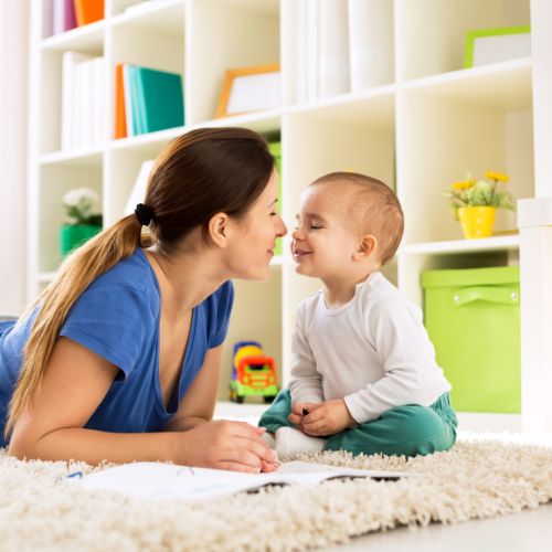 mother and son touching nose on a clean rug in their play room
