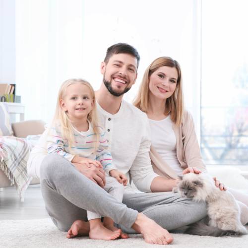 happy family sitting on the floor with cat in their lap