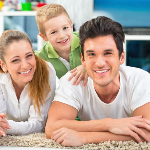 mother and father posing with their son on freshly cleaned rug